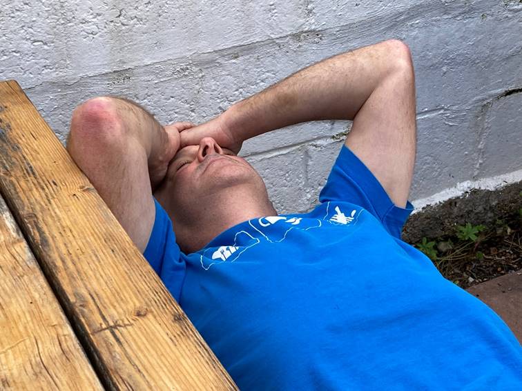 A person lying on a wooden bench

Description automatically generated with low confidence