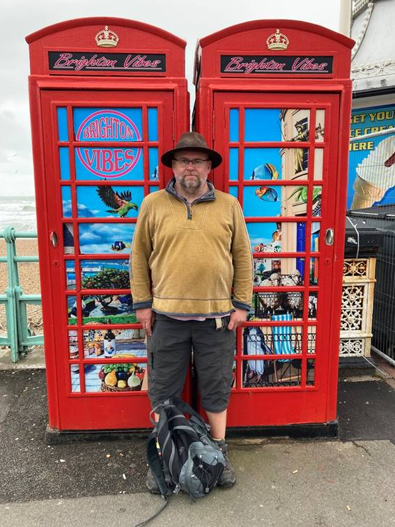 A person standing in front of a red telephone booth

Description automatically generated with medium confidence