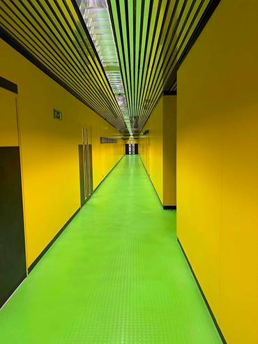 A long hallway with green floor and yellow walls

Description automatically generated