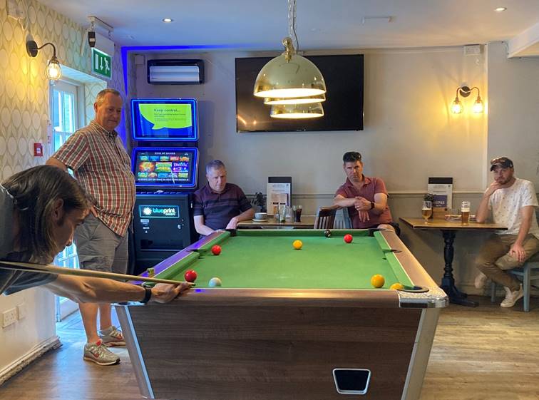 A group of men playing pool

Description automatically generated