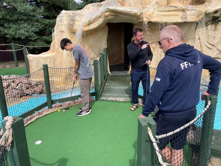A group of men playing mini golf

Description automatically generated