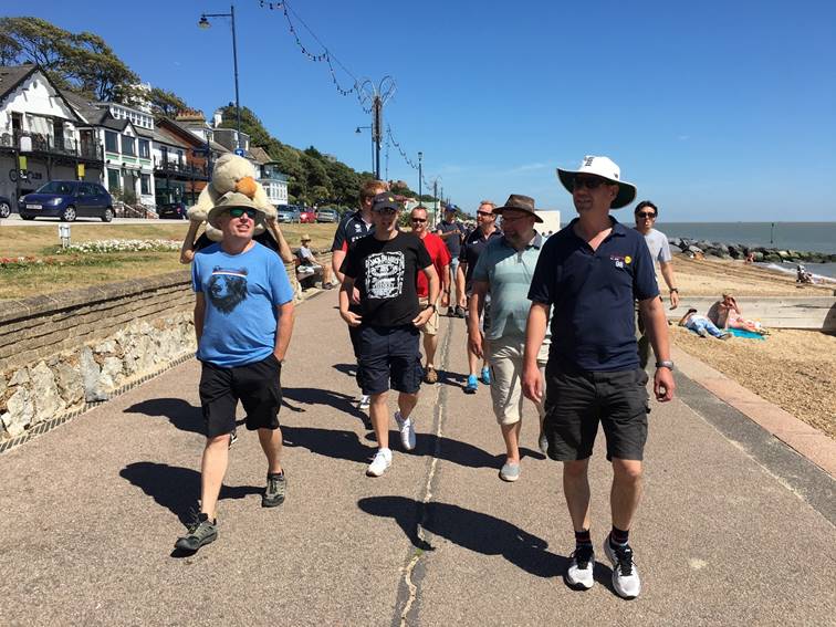 A group of people walking on a sidewalk

Description automatically generated