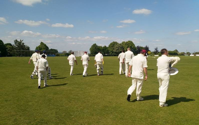 A group of people in white uniforms on a field

Description automatically generated
