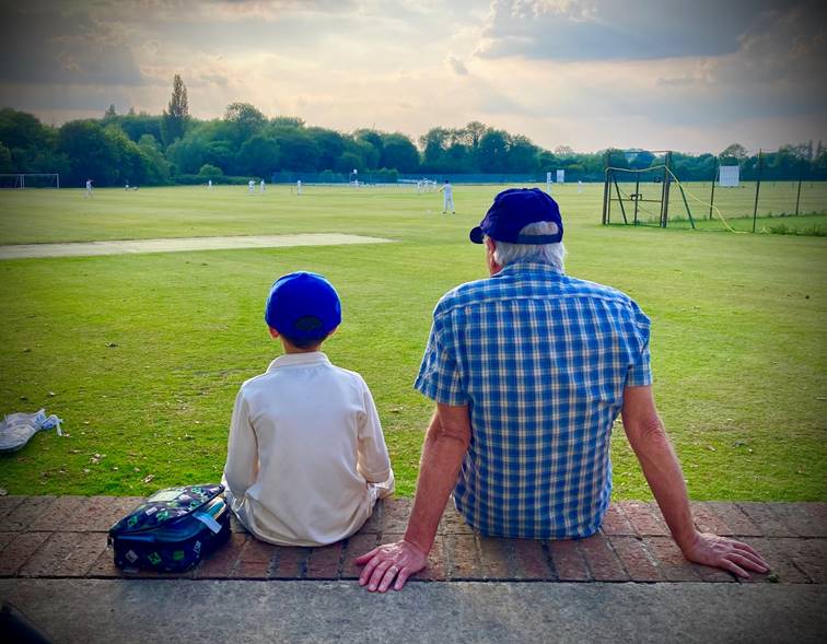 A person and child sitting on a brick wall in a field

Description automatically generated