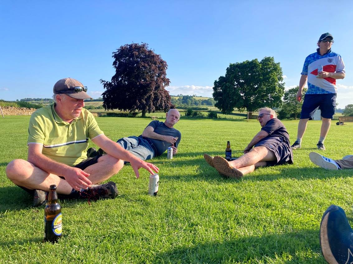 A group of men sitting on grass

Description automatically generated