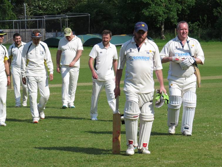 A group of men in white uniforms walking on a field

Description automatically generated