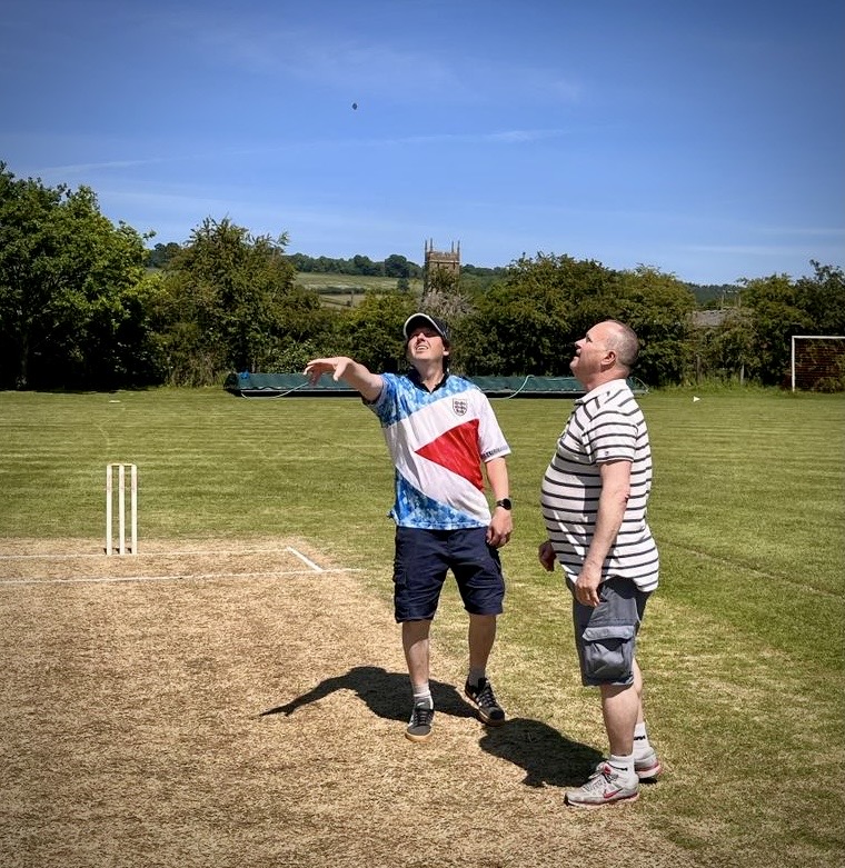 A person standing on a grass field with another person pointing

Description automatically generated